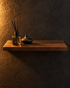 Brown wooden floating shelf styled against a charcoal wall